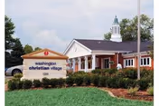 Exterior view of a senior living facility with a brick entrance and sign.