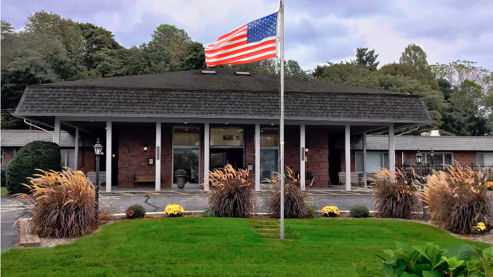 Exterior view of Harbor Village North, a brick senior living facility with a front entrance.