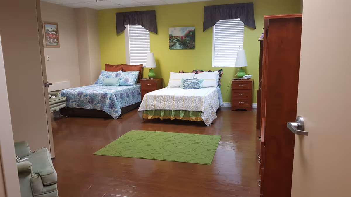 Bright shared bedroom with two beds, nightstands, lamps, and a green rug.