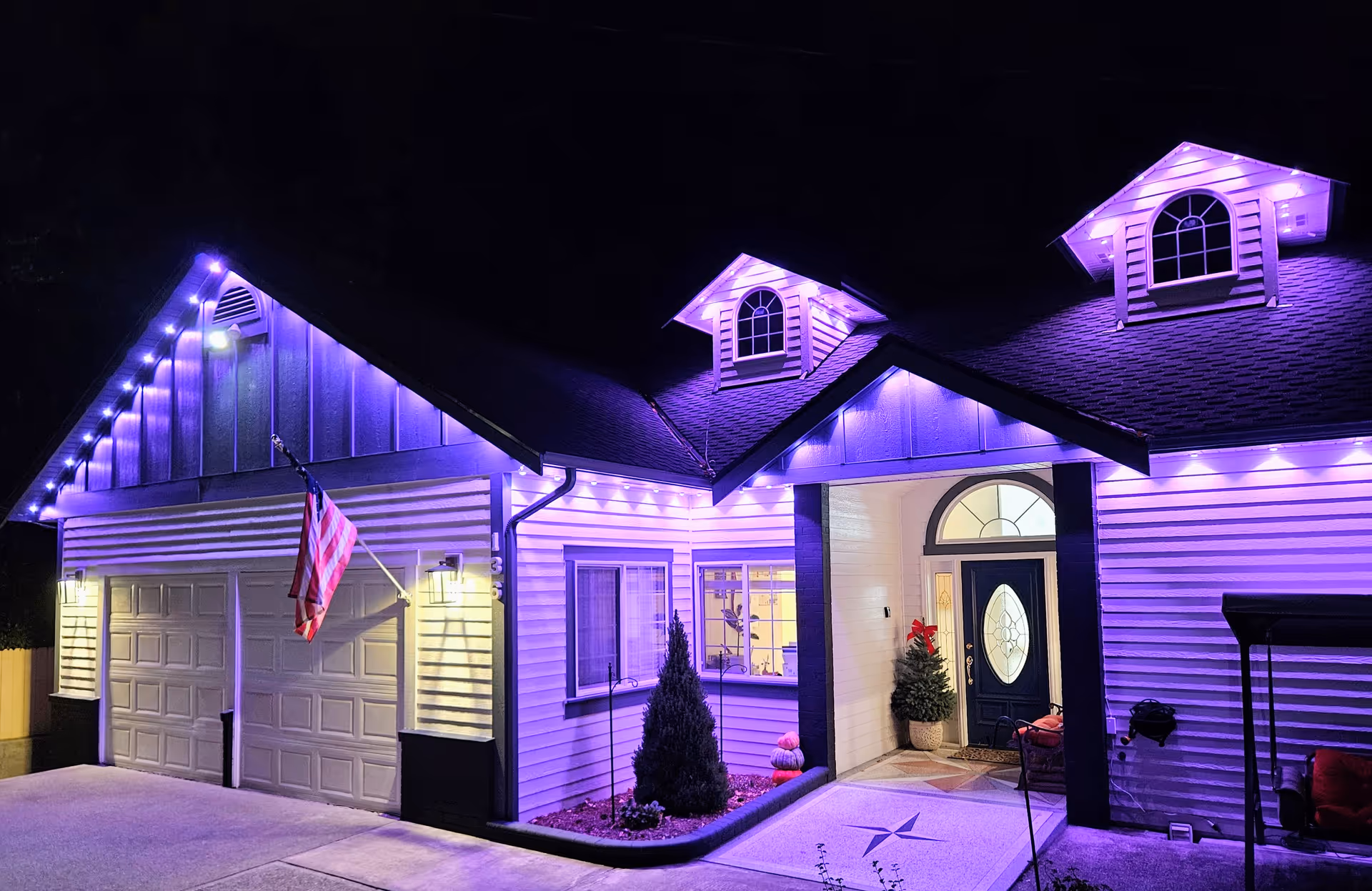 Nighttime exterior of a front entrance with purple lights and an American flag.