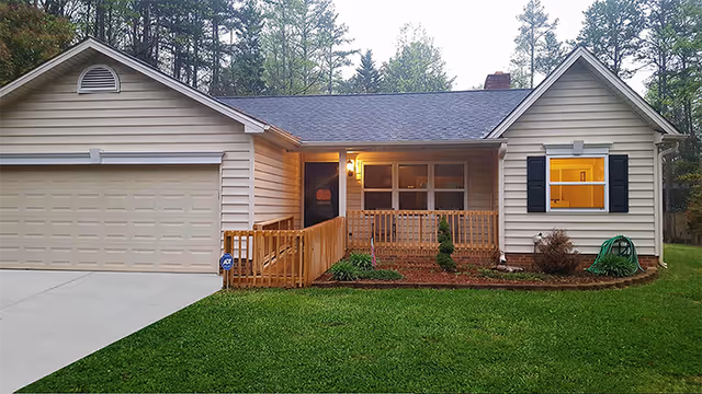 Exterior of a single-story house with a front porch, ramp, and attached garage.