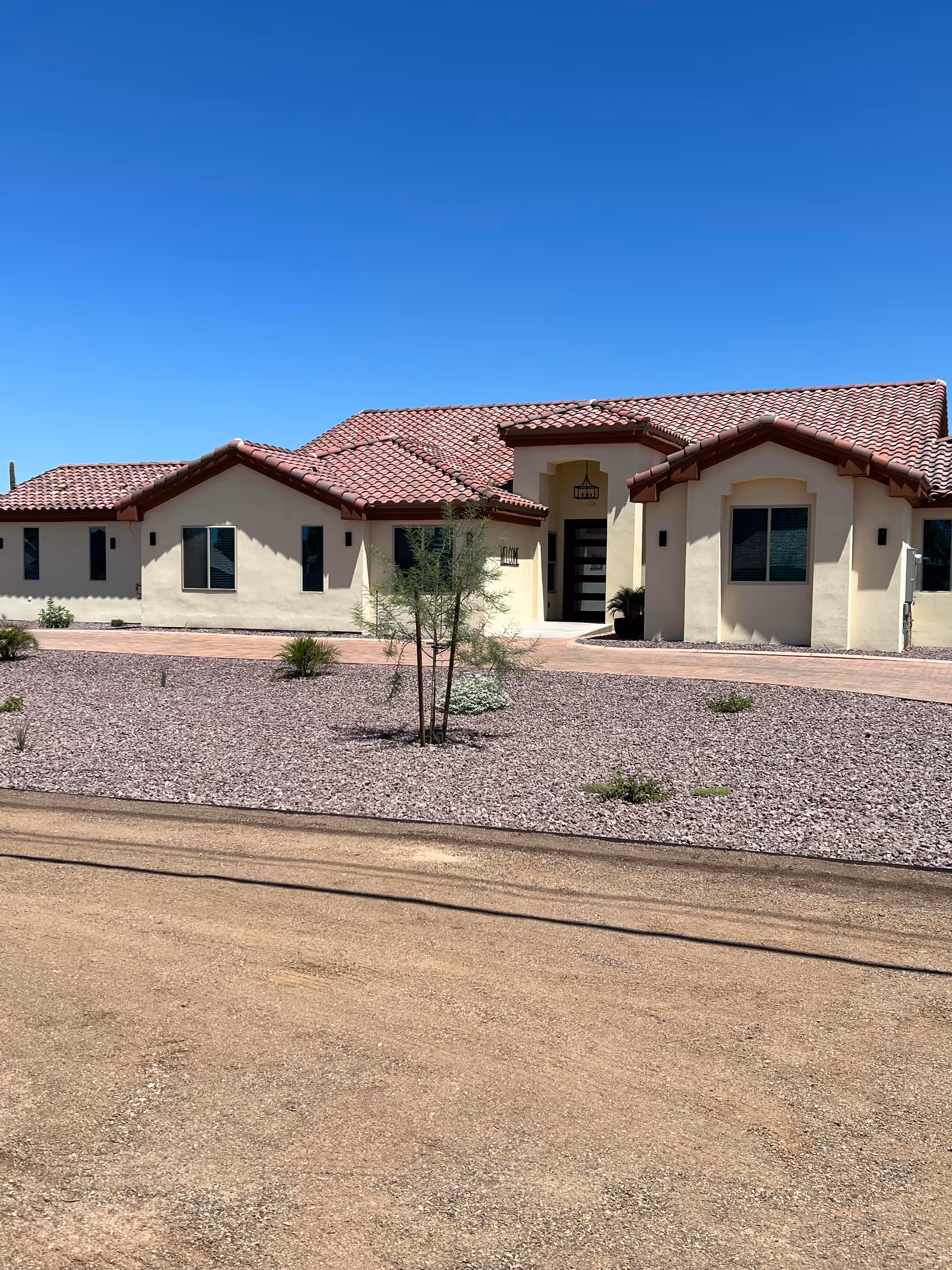 Front exterior of a beige Pinnacle Peak Senior Living building with red-tiled roof and desert landscaping.