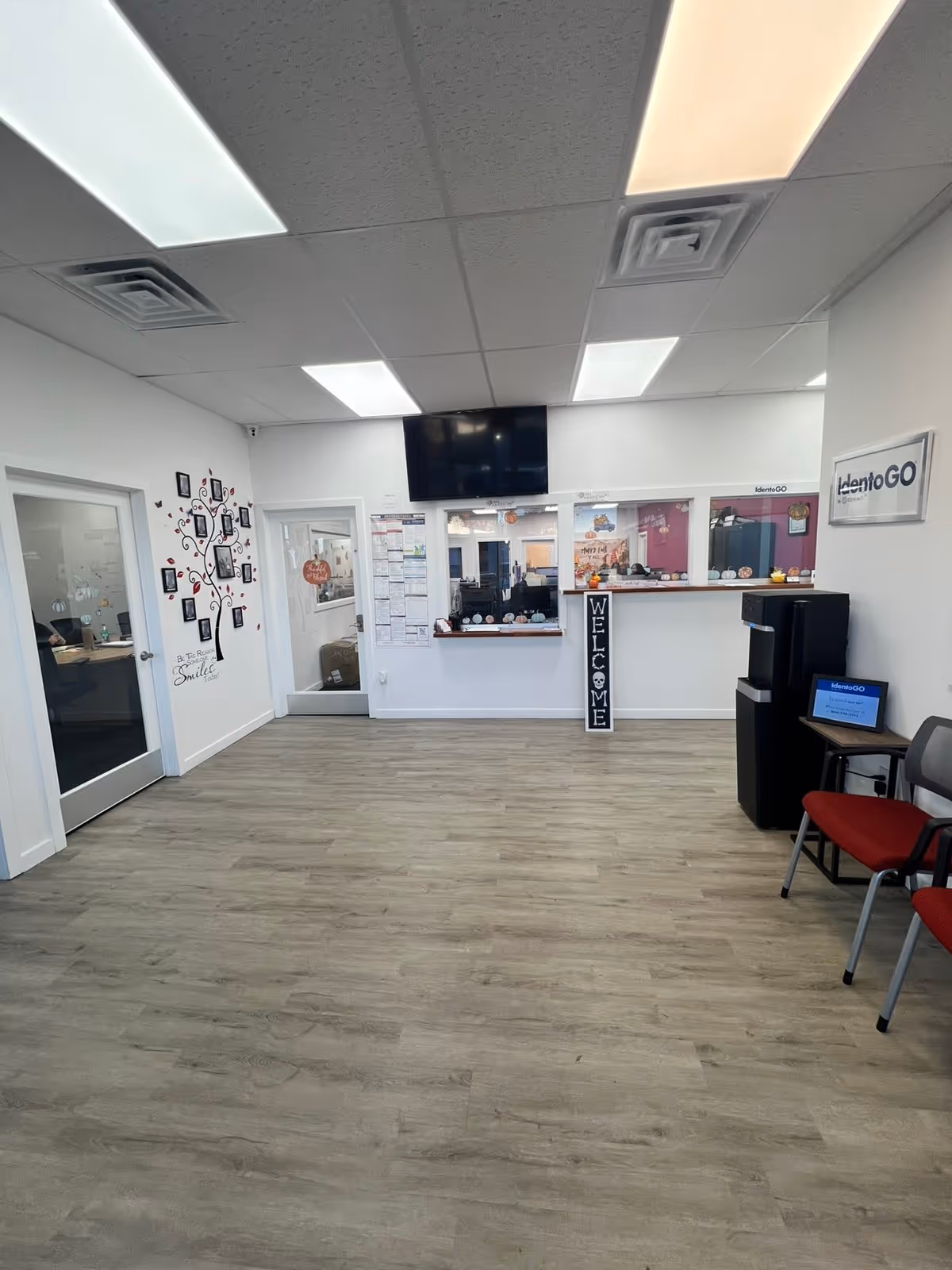 Interior reception area with a front desk, welcome sign, TV, and chairs.