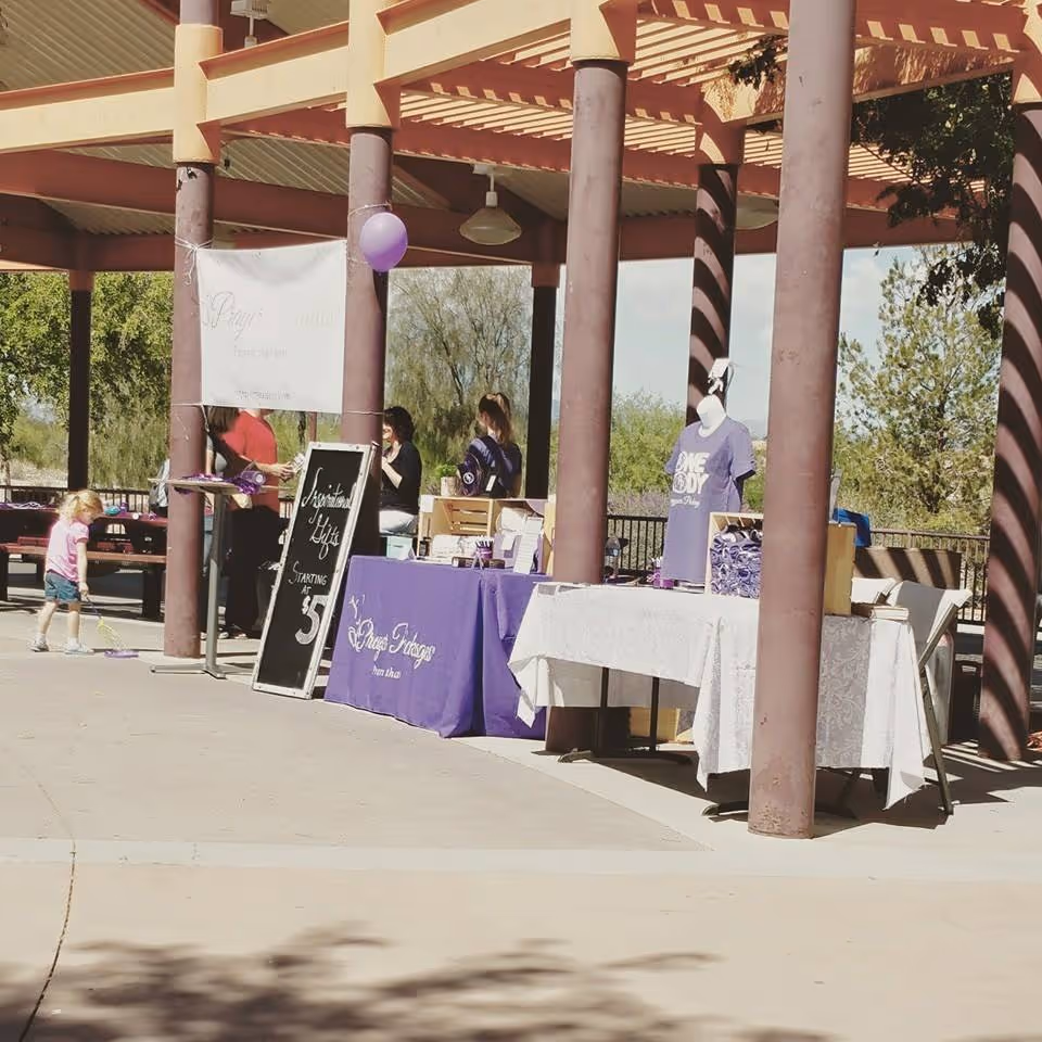 Outdoor pavilion event with tables, banners, and people at a care-provider booth.