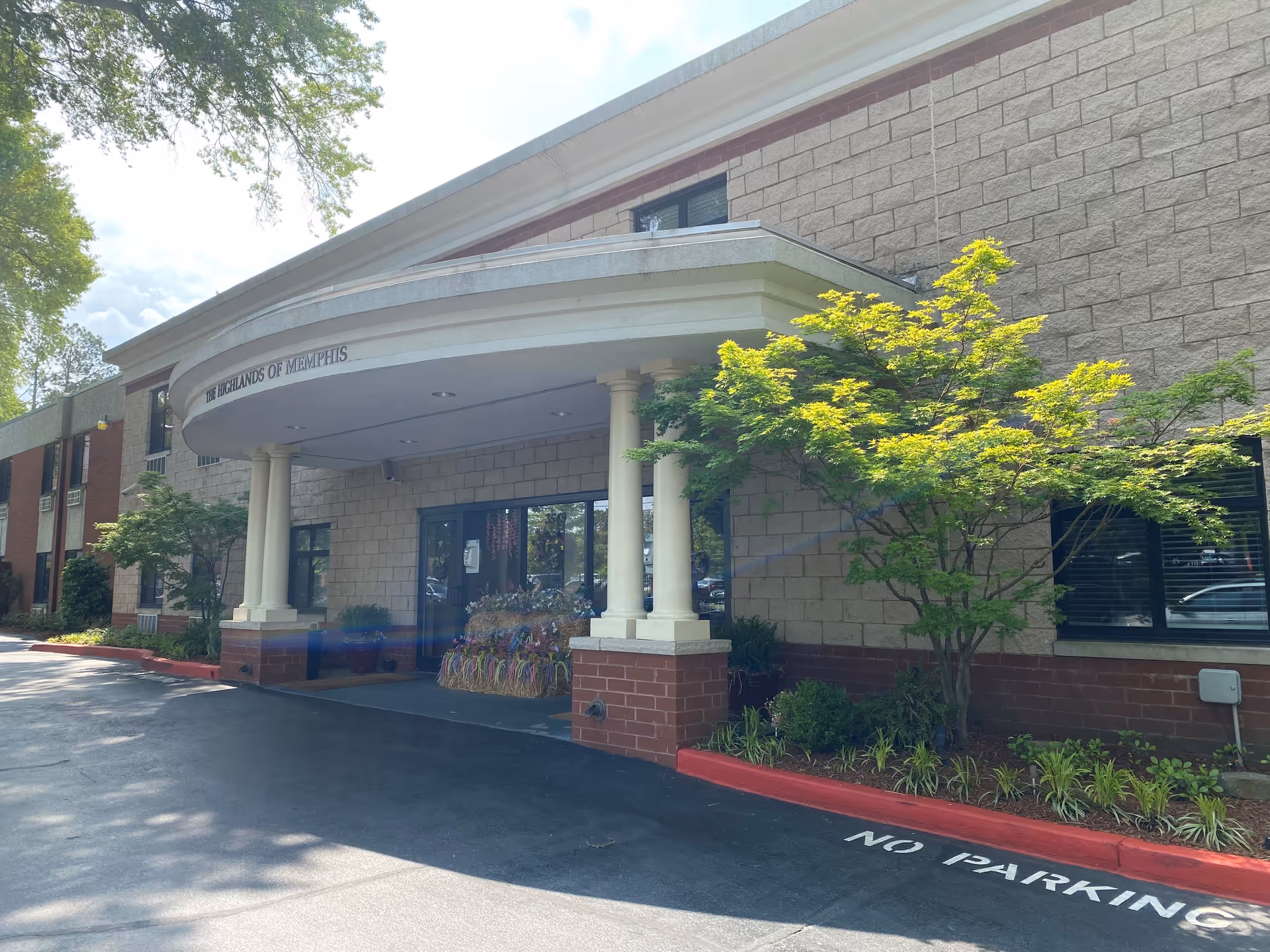 Exterior view of The Highlands of Memphis entrance with a curved canopy and columns.