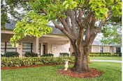 Front view of West Melbourne Health and Rehabilitation Center with a large tree and sign.