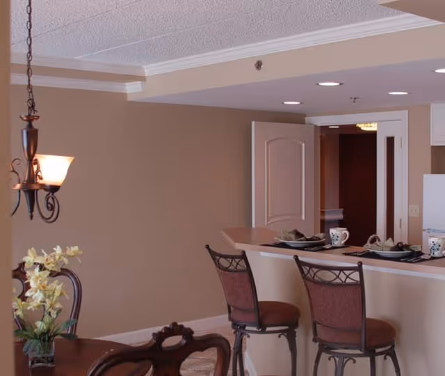 Interior dining area with a high counter, bar stools, and dishes set near an open doorway.