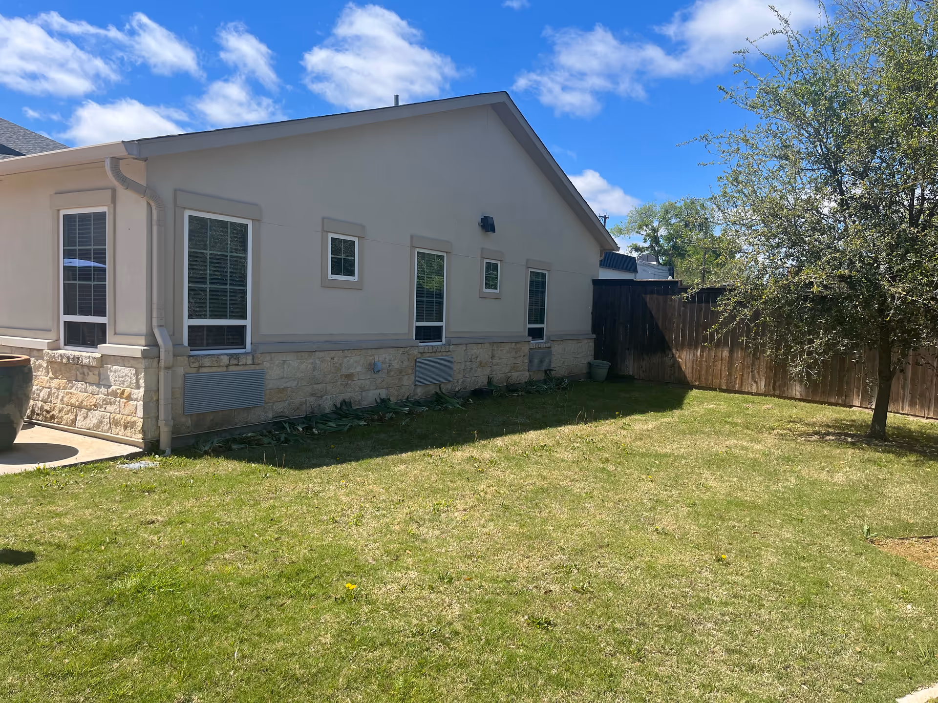 Single-story beige memory care building with stone base, windows, and a grassy yard.