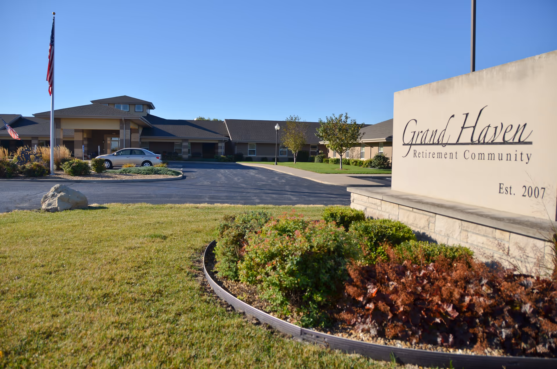 Front exterior view of Grand Haven Retirement Community with sign and landscaped foreground.