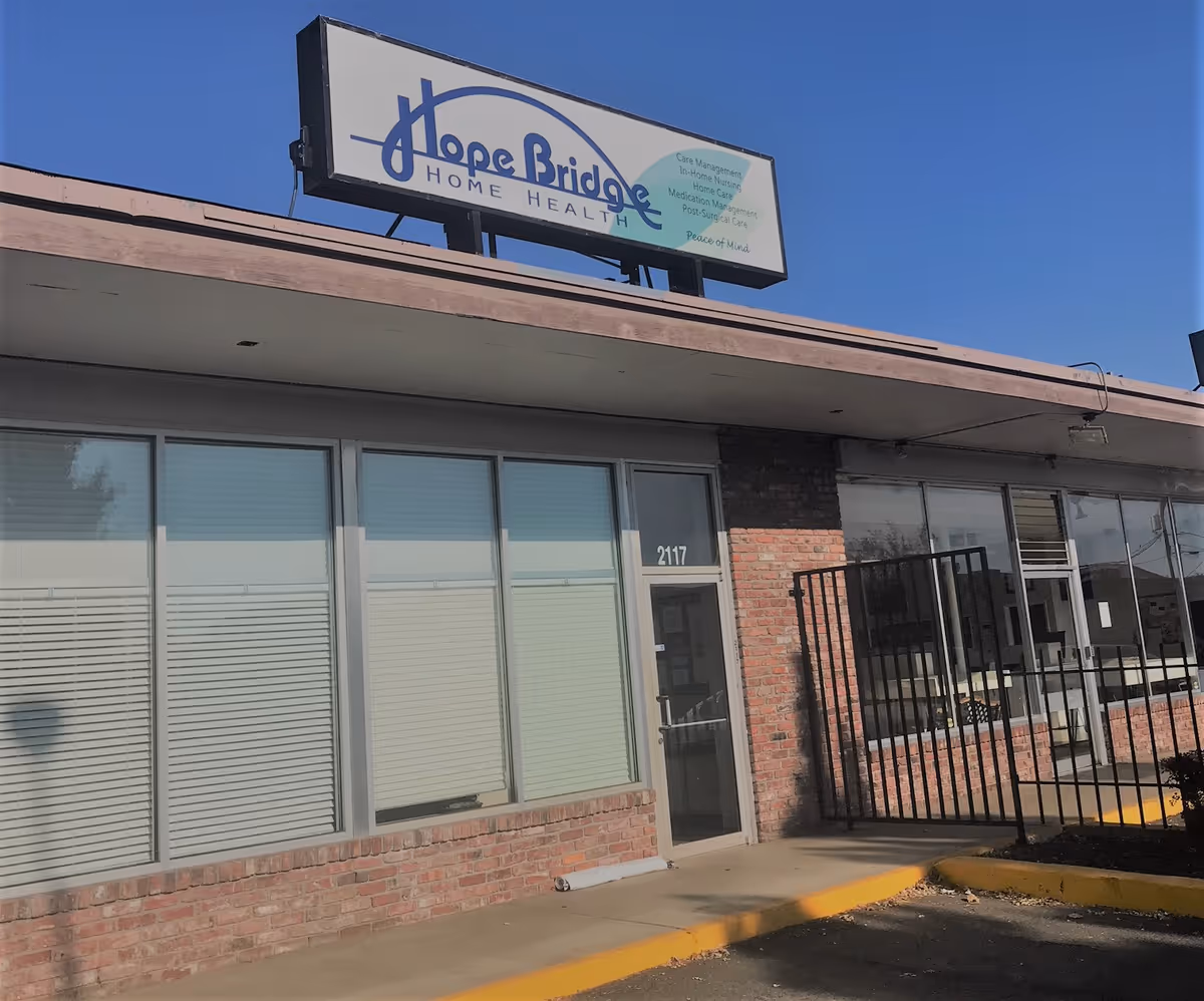 Exterior of HopeBridge Home Health building with brick facade, large windows, and gated entrance.