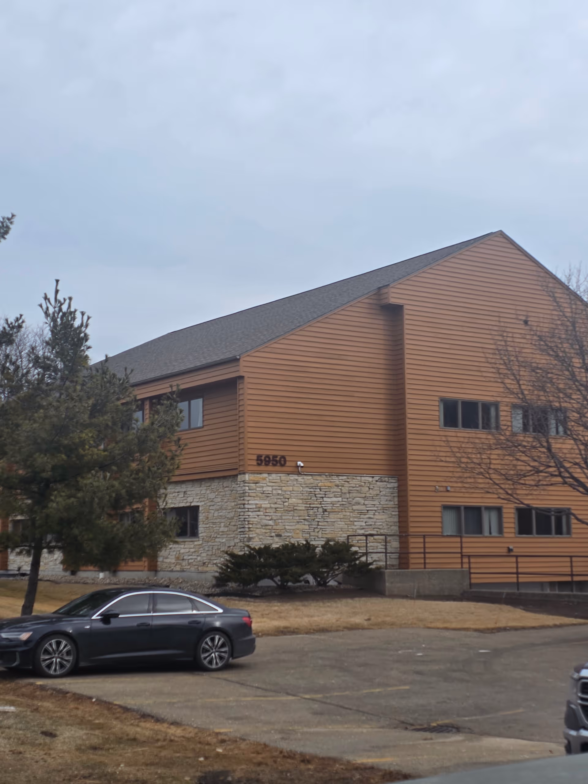 Exterior view of a brown building with stone base and parked cars