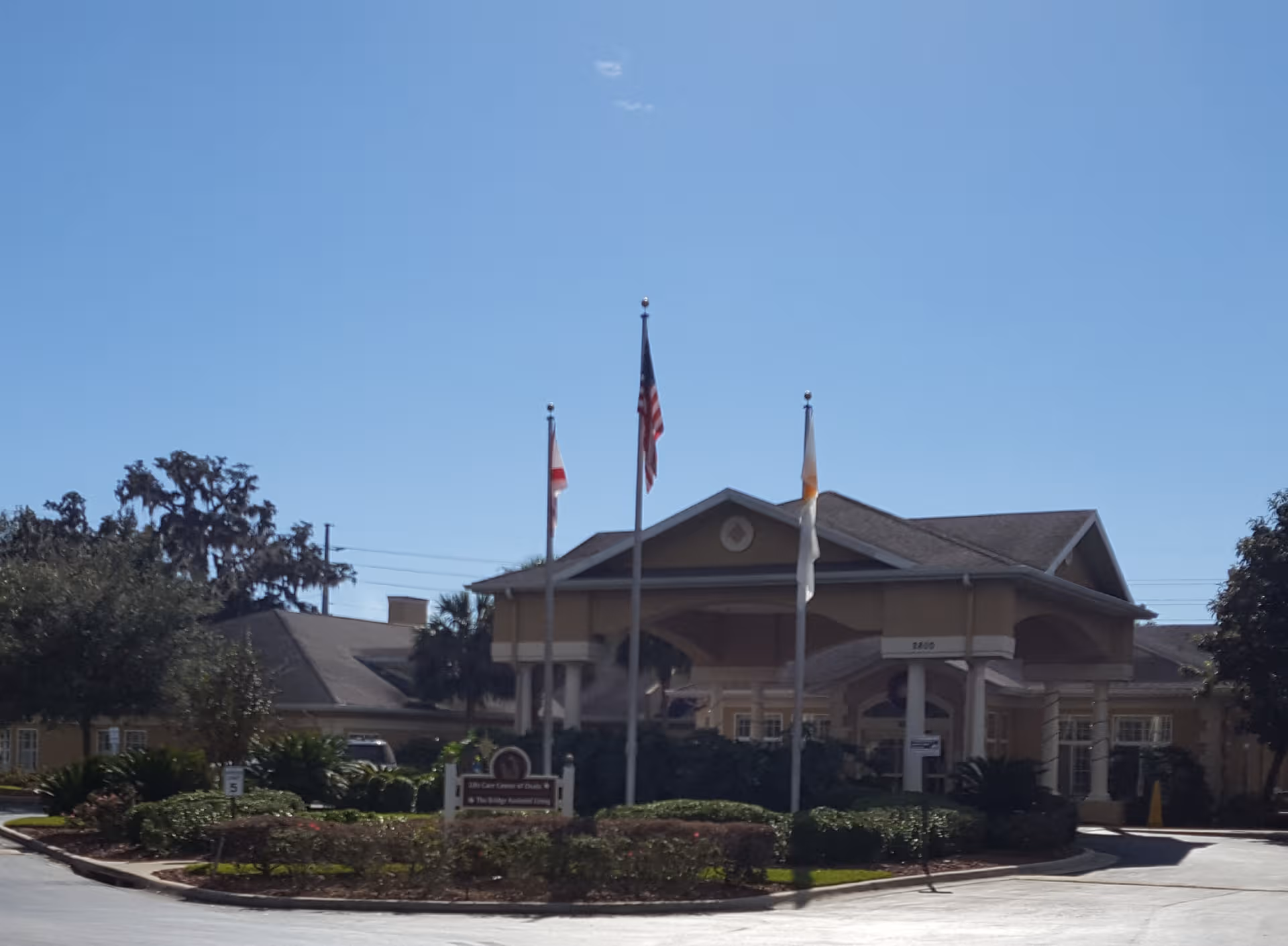 Front view of The Bridge at Ocala with flags and landscaped entrance.