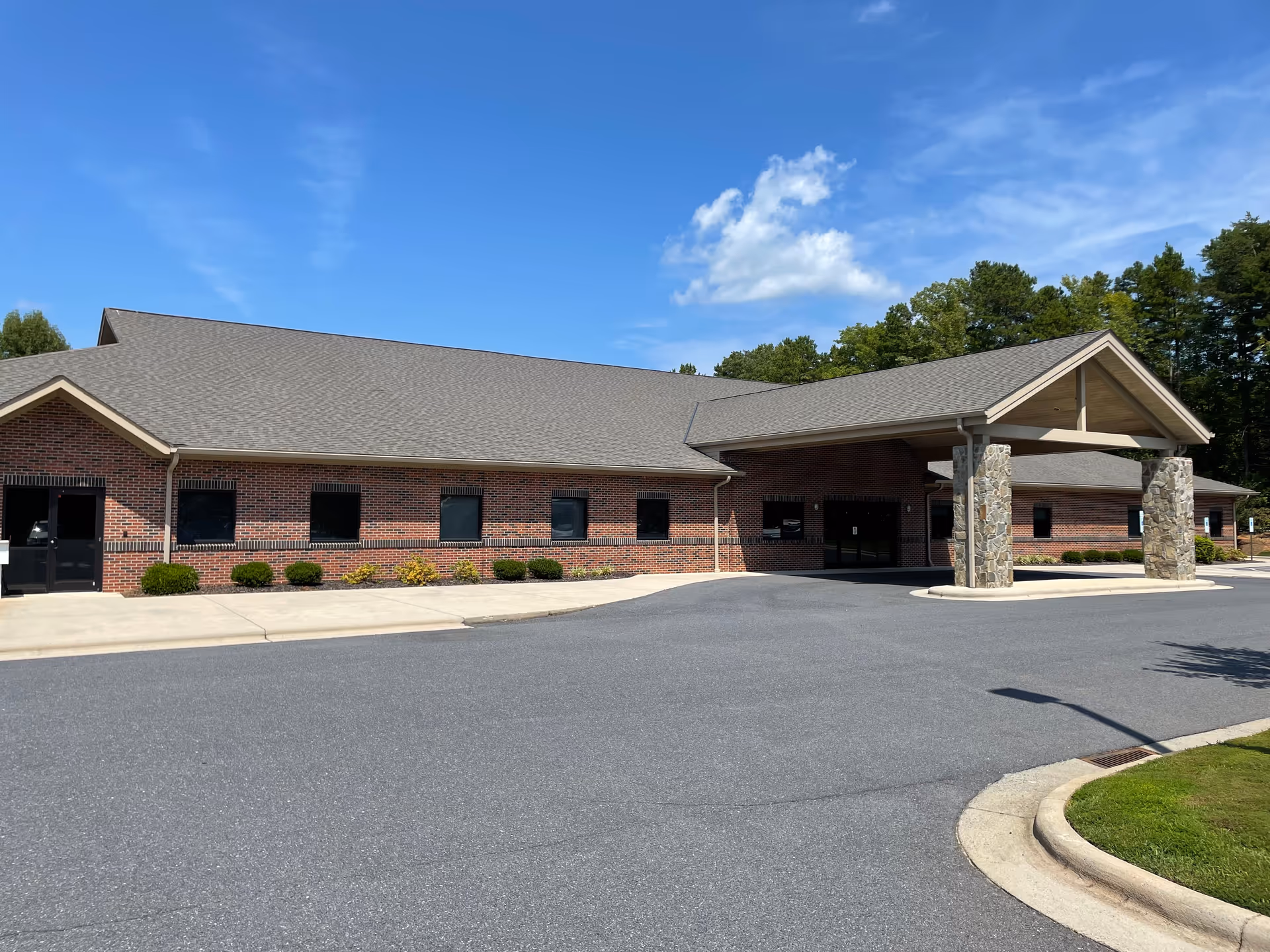 Exterior view of a brick senior care building with a covered entrance and driveway.