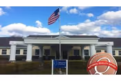 Front view of Sullivan Park Care Center entrance with flag and blue sky.