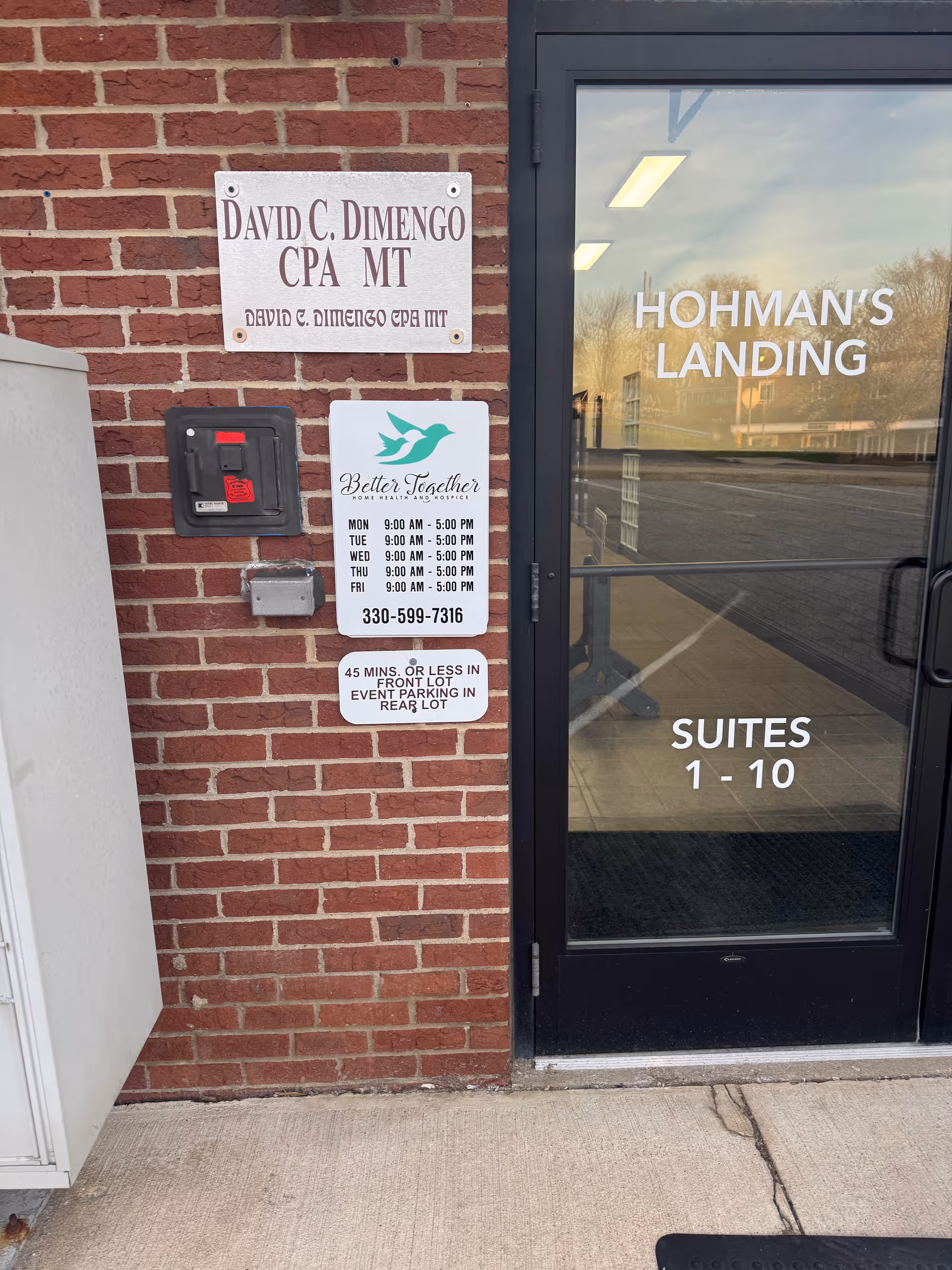 Brick exterior with Better Together Home Health and Hohman's Landing Suites signs beside a door.