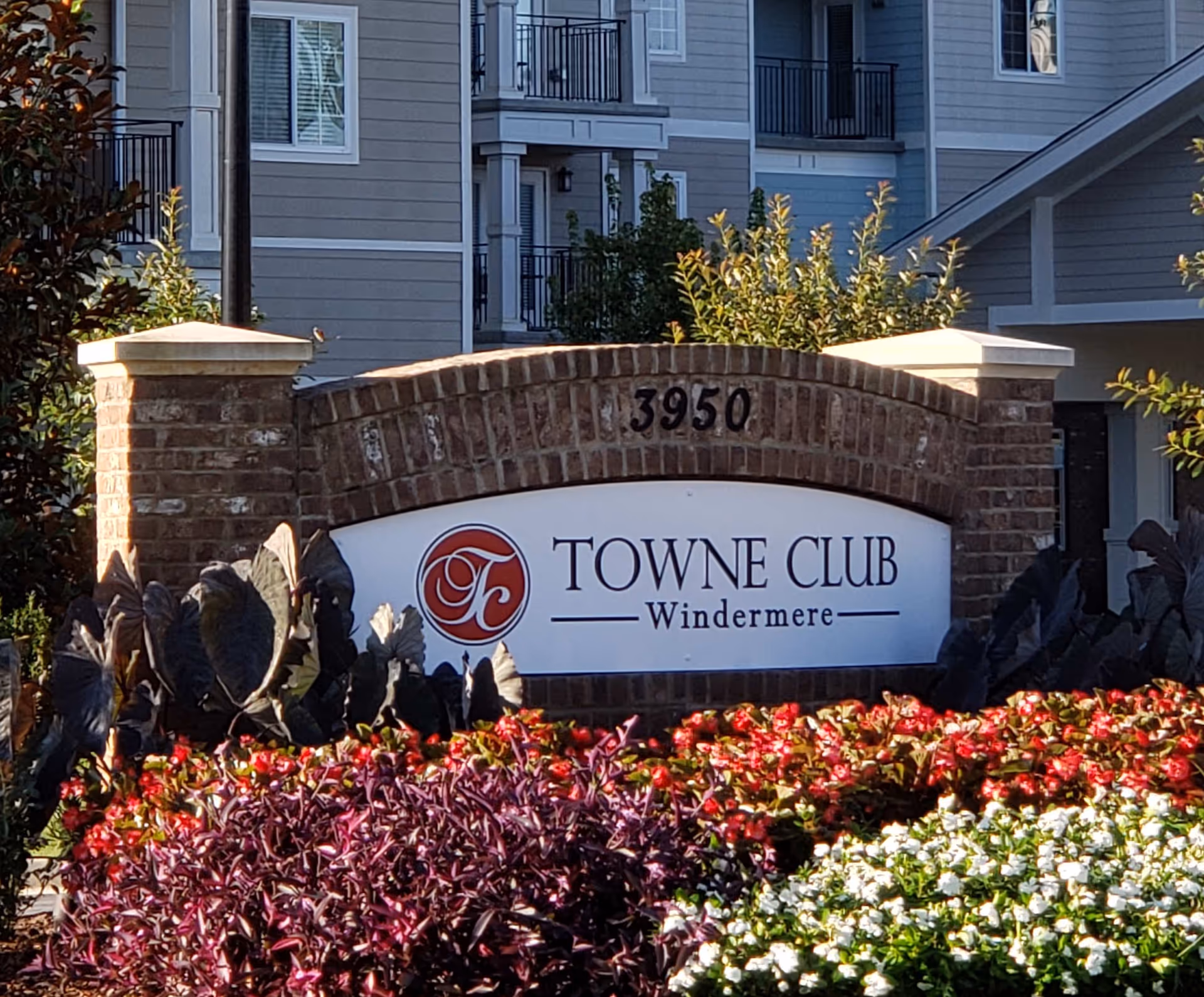 Brick entrance sign for Towne Club Windermere with surrounding landscaping.