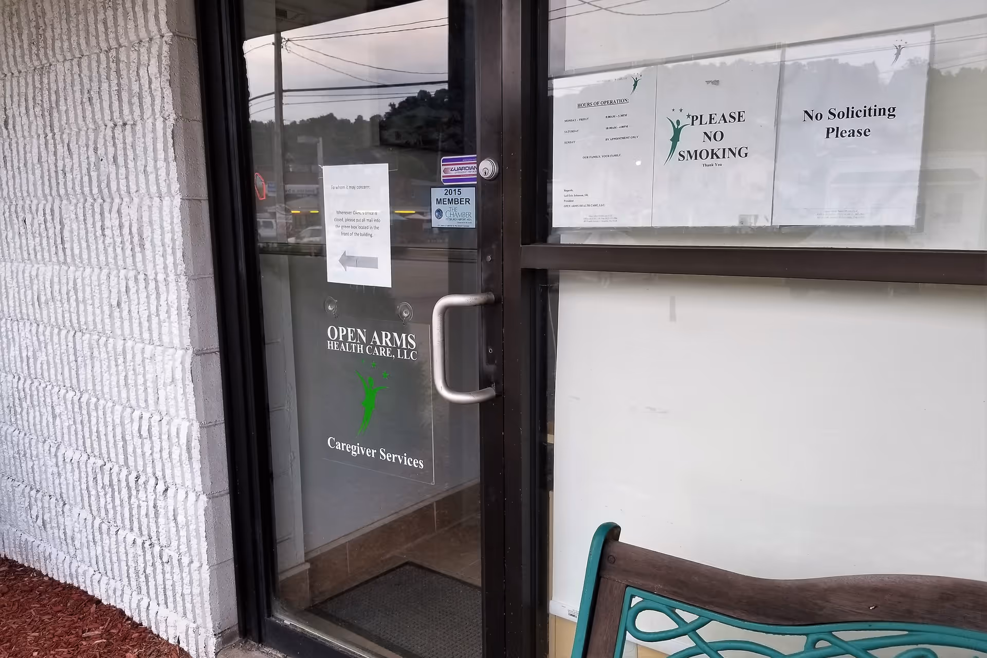 Glass entrance door for Open Arms Health Care with signage, bench, and brick exterior.
