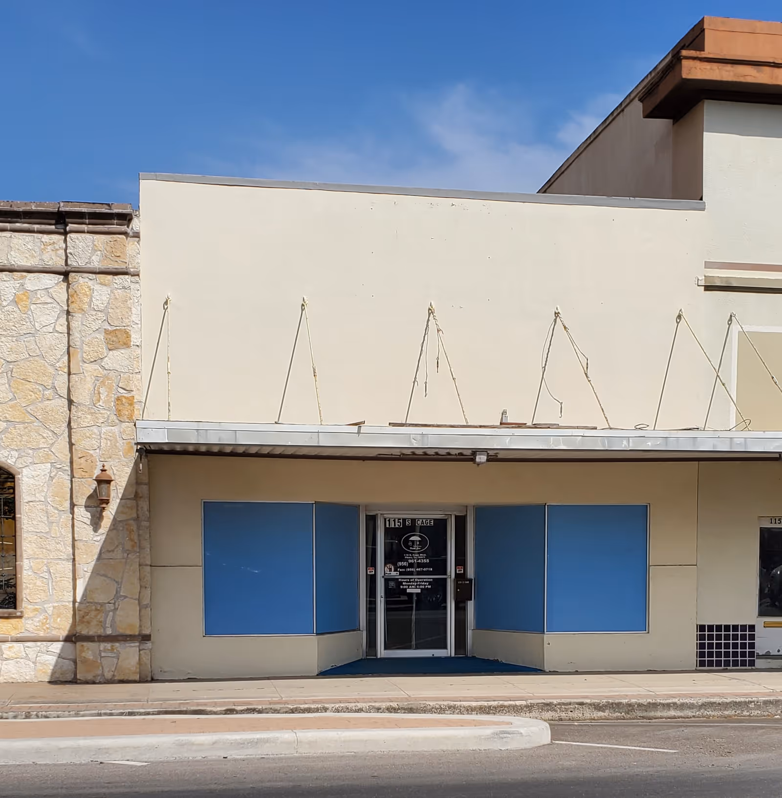 Front facade of a beige building with blue storefront panels and glass entrance.