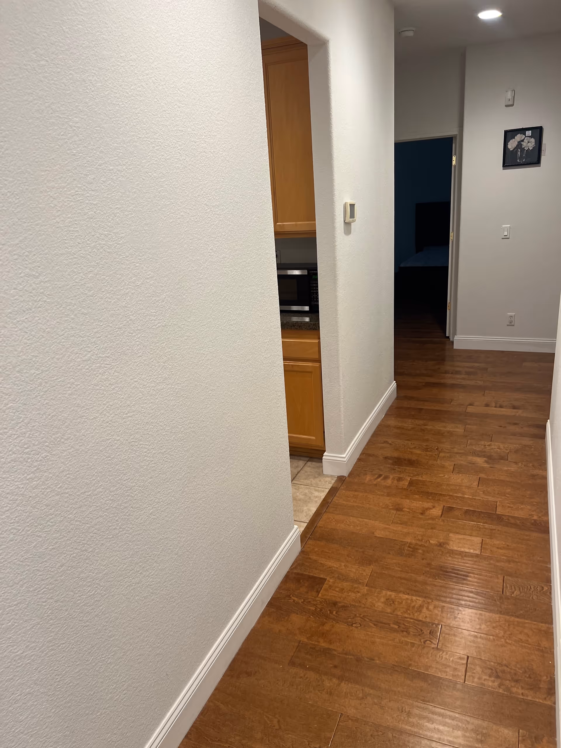 Interior hallway of a senior living facility showing a kitchen doorway and distant bedroom.