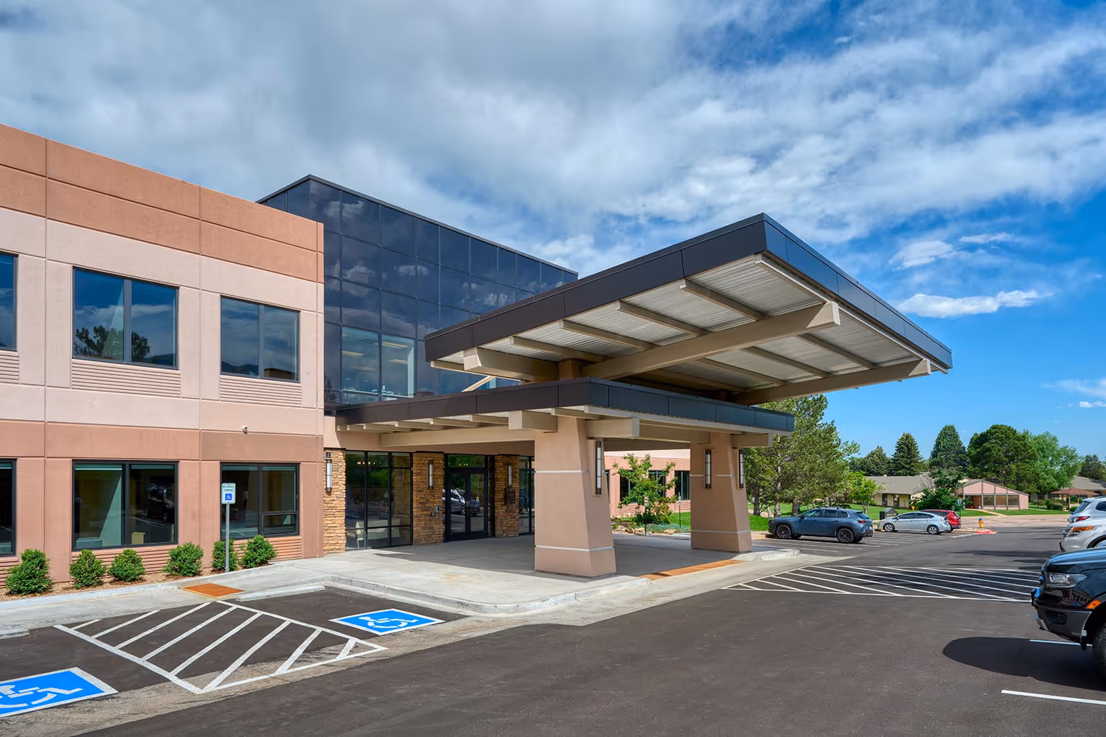 Modern hospice building exterior with a covered entrance and parking lot.