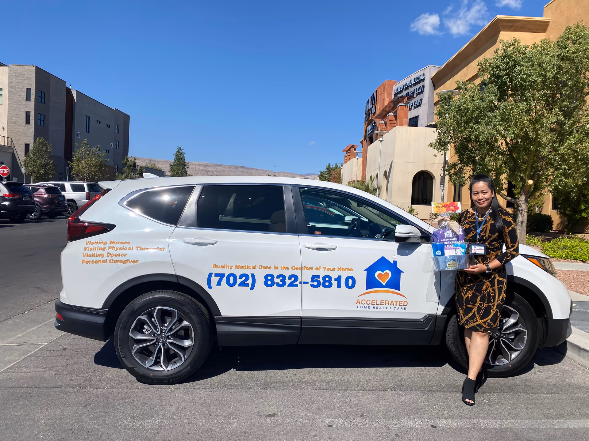 White Accelerated Home Health Care vehicle parked in a lot beside a smiling staff member.