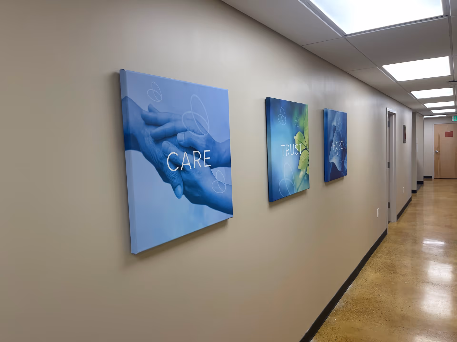 Long hallway with three blue wall art panels reading CARE, TRUST, HOPE.