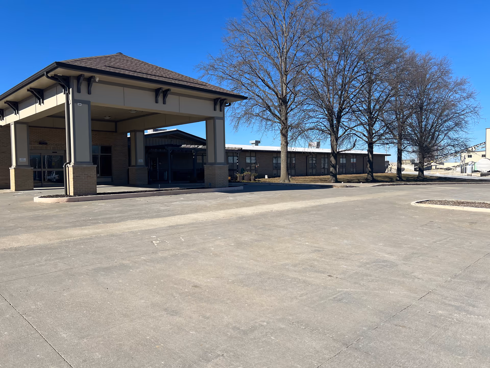 Exterior view of Lutheran Good Shepherd Home entrance with a covered porte-cochere and leafless trees