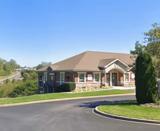 Exterior view of a single-story senior care facility with entrance and landscaped grounds.
