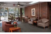 Cozy senior living lounge with brick walls, comfortable seating, and large glass doors to the outside.