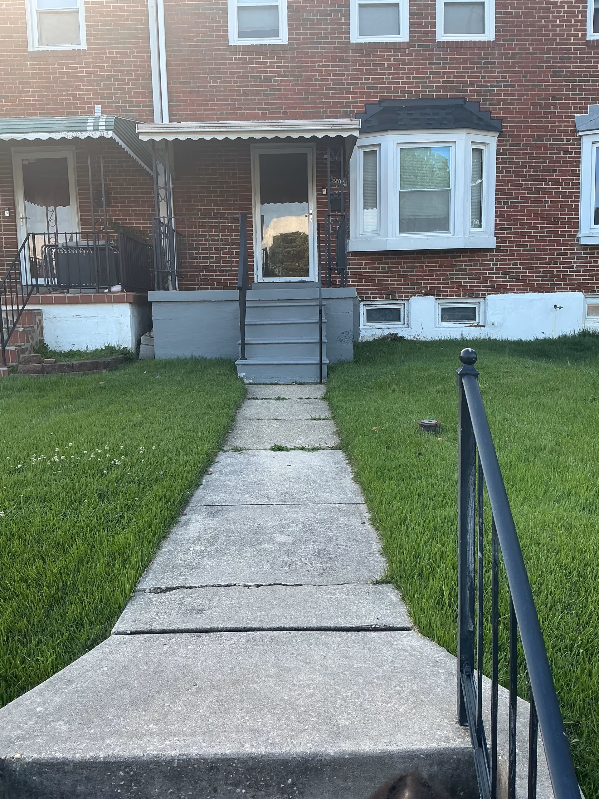 A brick residential building exterior with front steps, a walkway, and a porch.