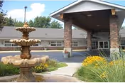 Exterior view of Brittany Manor with a covered entrance, fountain, and landscaped walkway.