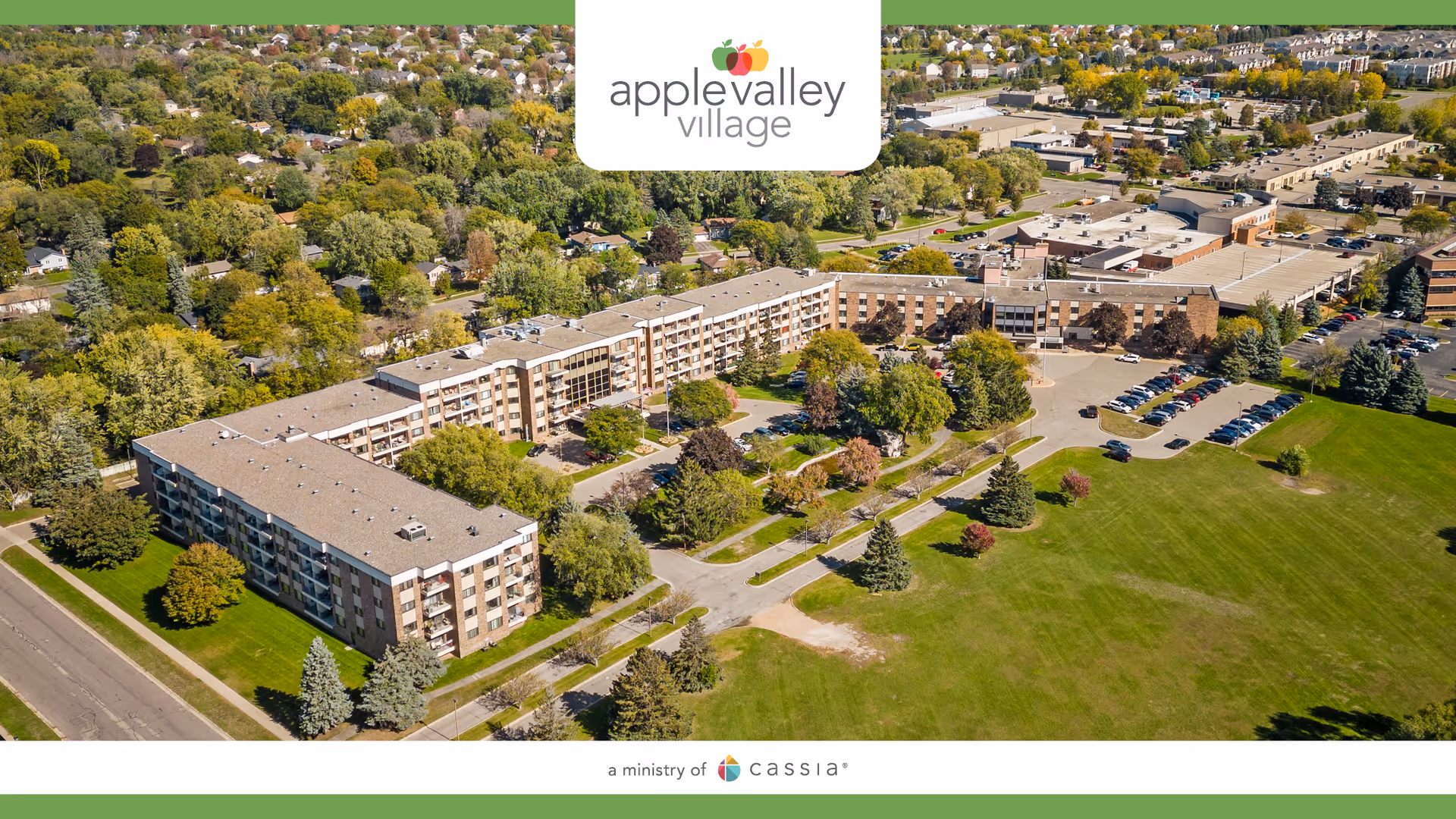 Aerial view of a multi-building senior living campus with green lawns and parking.