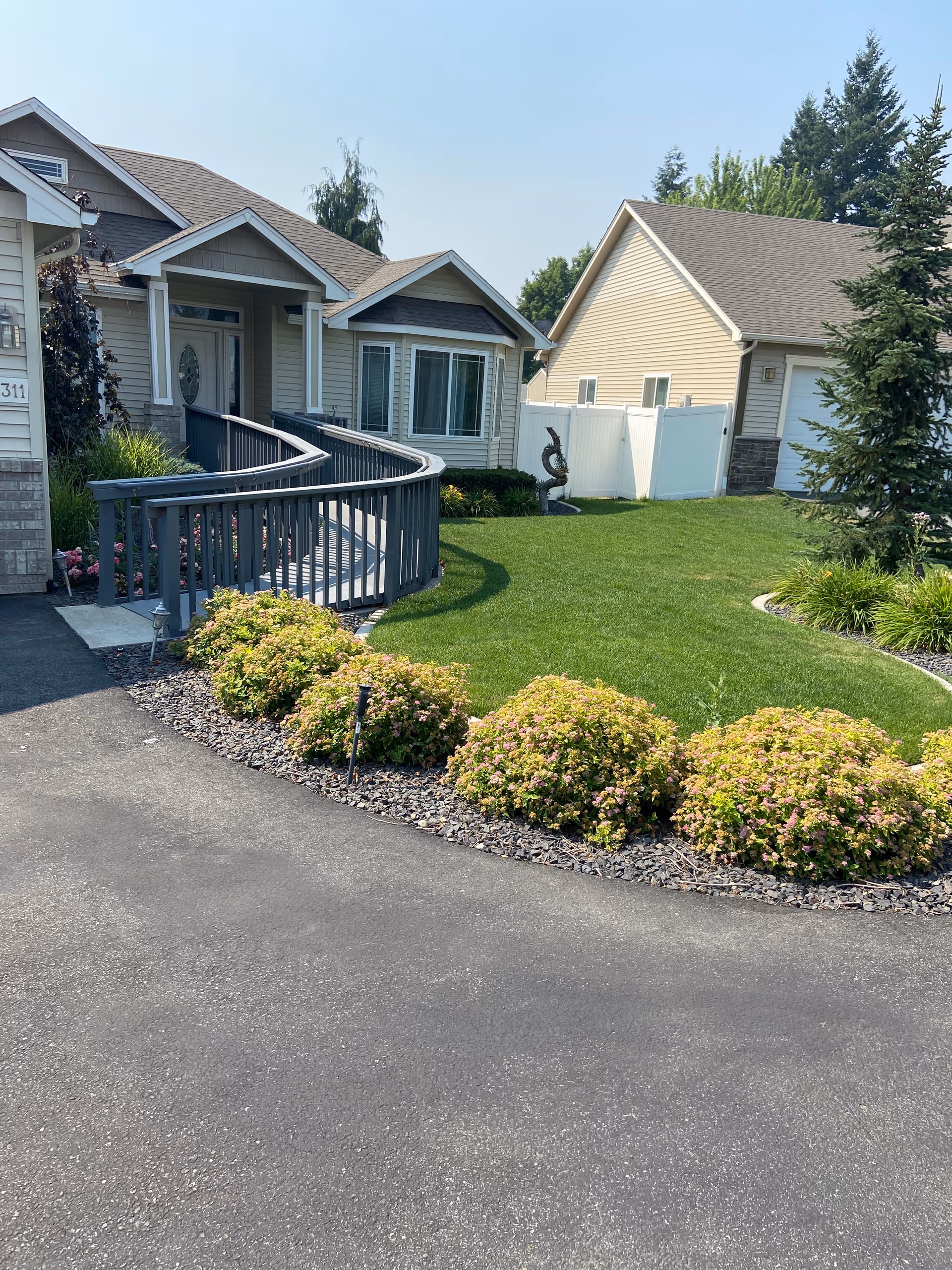 Front view of Serene Adult Family Home with curved ramp, manicured lawn, and shrubs.