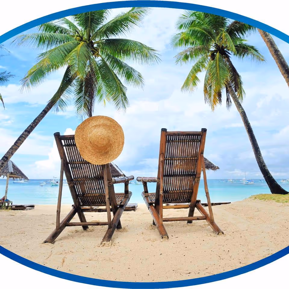 Two wooden beach chairs on sandy shore with palm trees and turquoise sea.