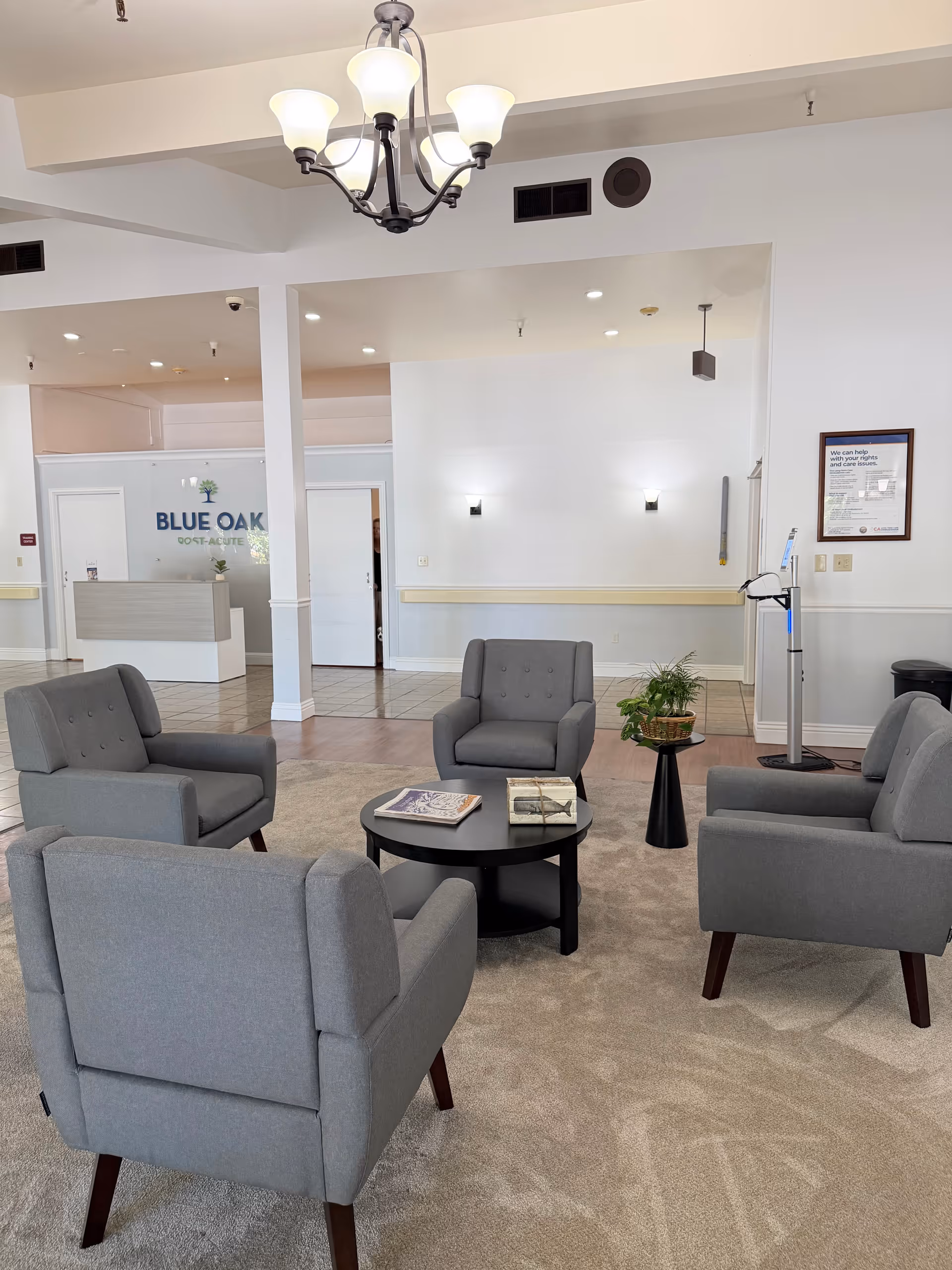 Grey lounge chairs surround a round black coffee table in a bright lobby.