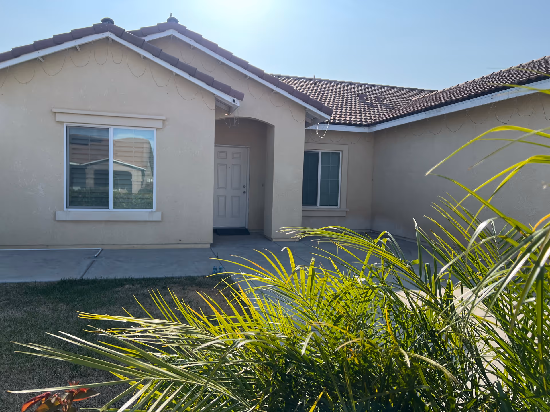 Front exterior view of a beige senior care home with a doorway and window.