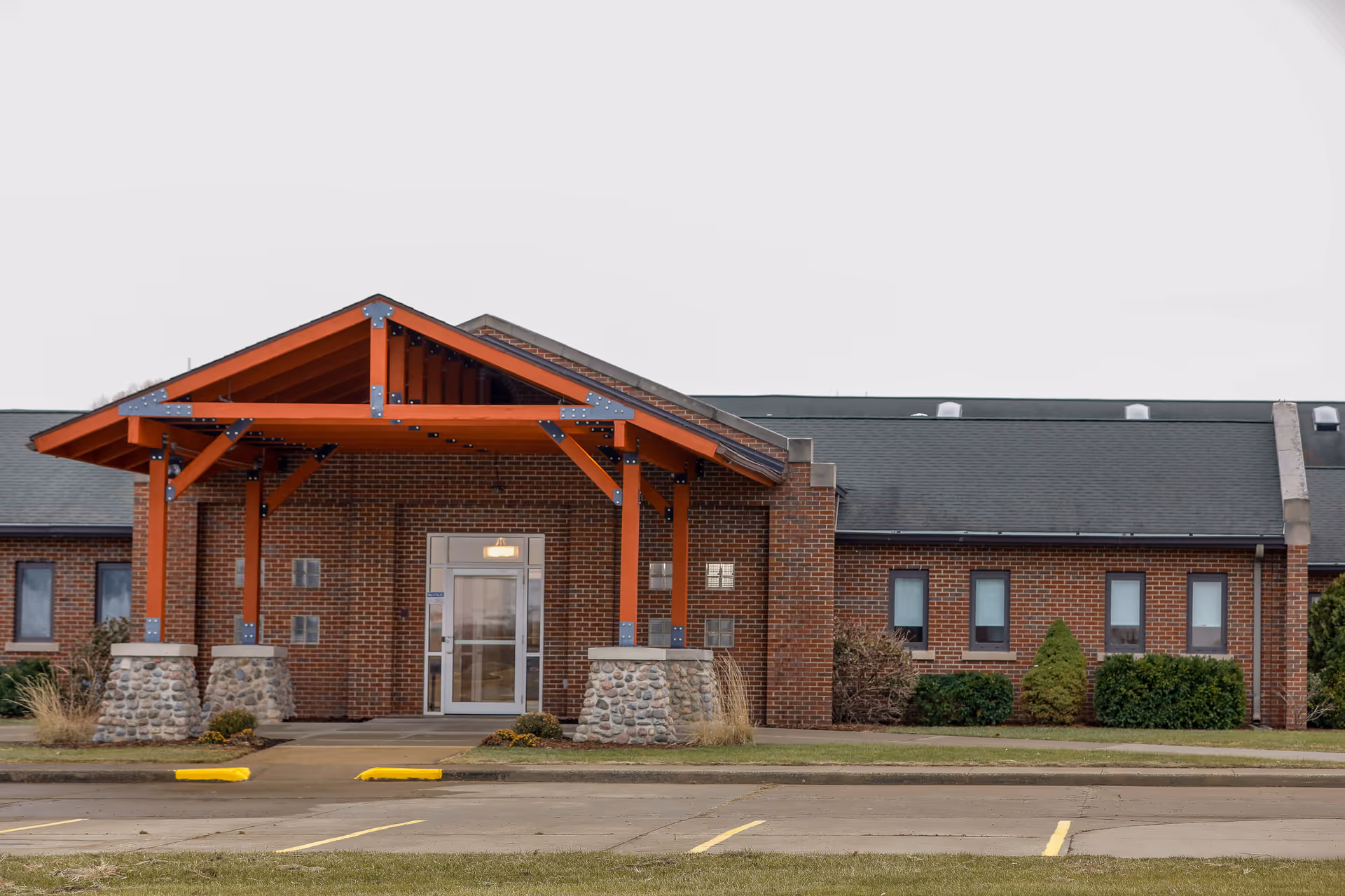 Brick facility entrance with a red wooden canopy and glass doors.