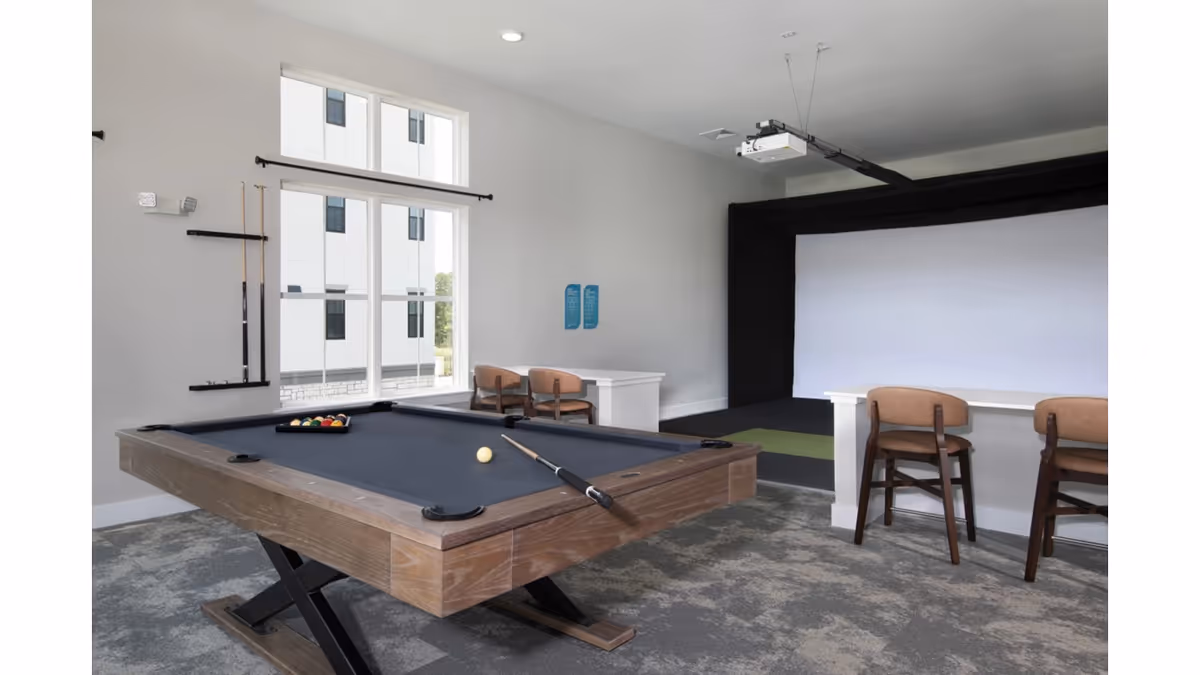 Interior recreation room featuring a pool table, projector screen, and seating area.