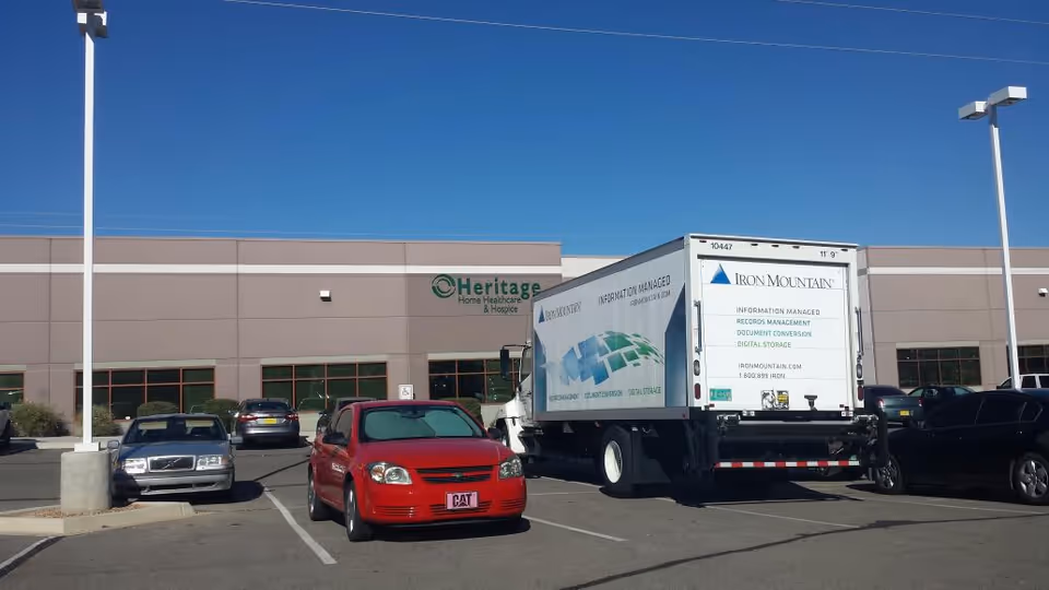 Exterior view of Heritage Home Healthcare & Hospice building in Albuquerque with parked cars and truck.