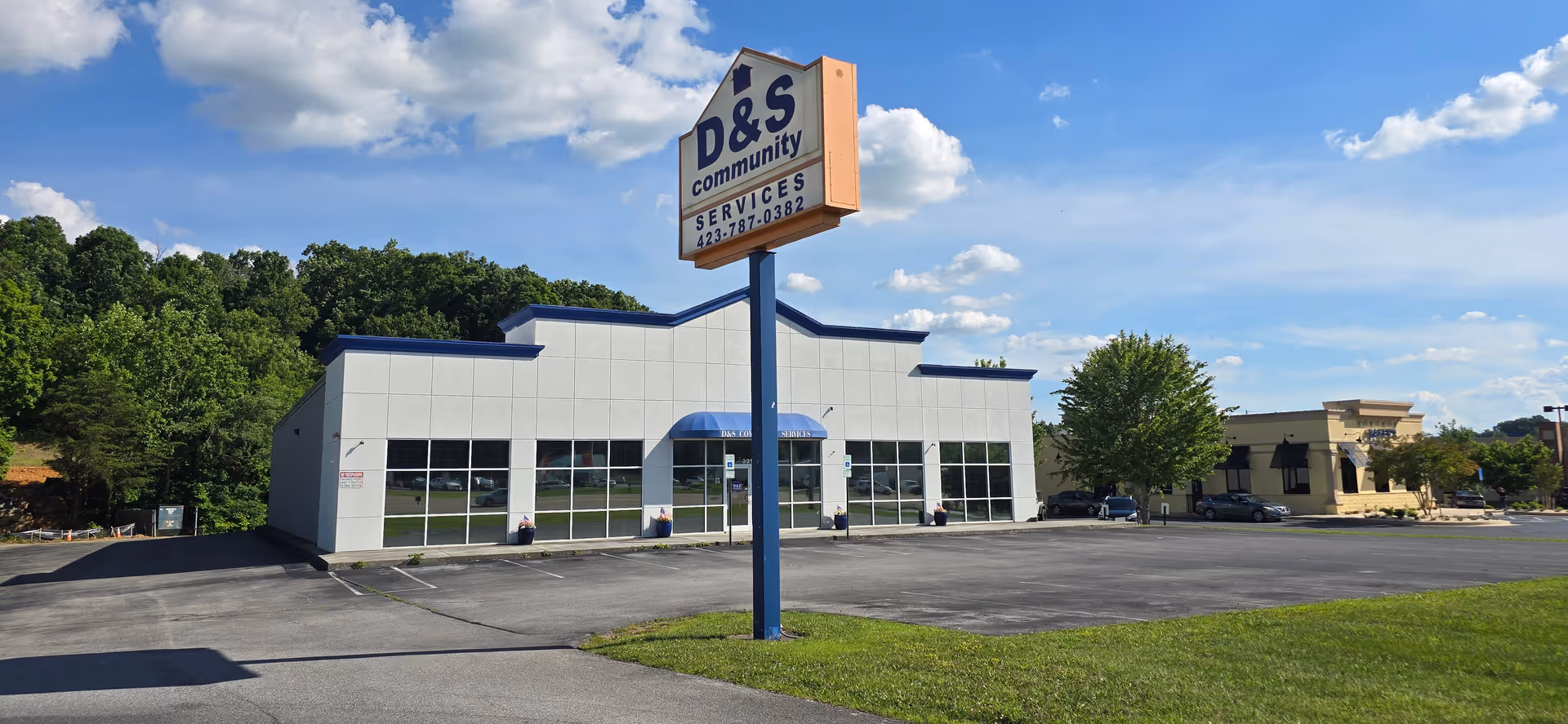 Exterior view of a senior living building with a D&S Community Services sign in parking lot.