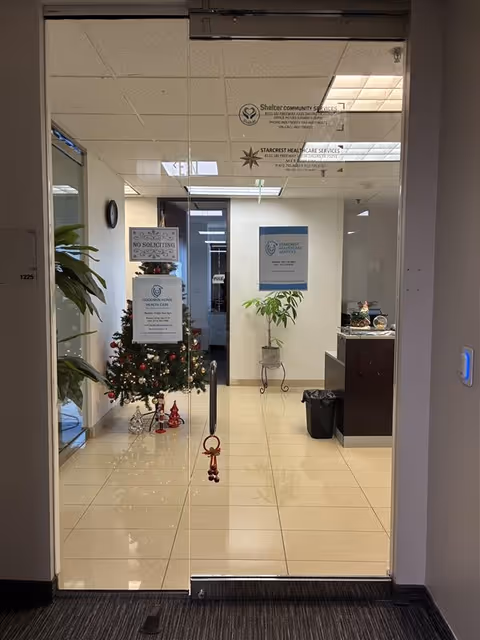 Glass entry doors open to a reception area with plants, signs and a Christmas tree.