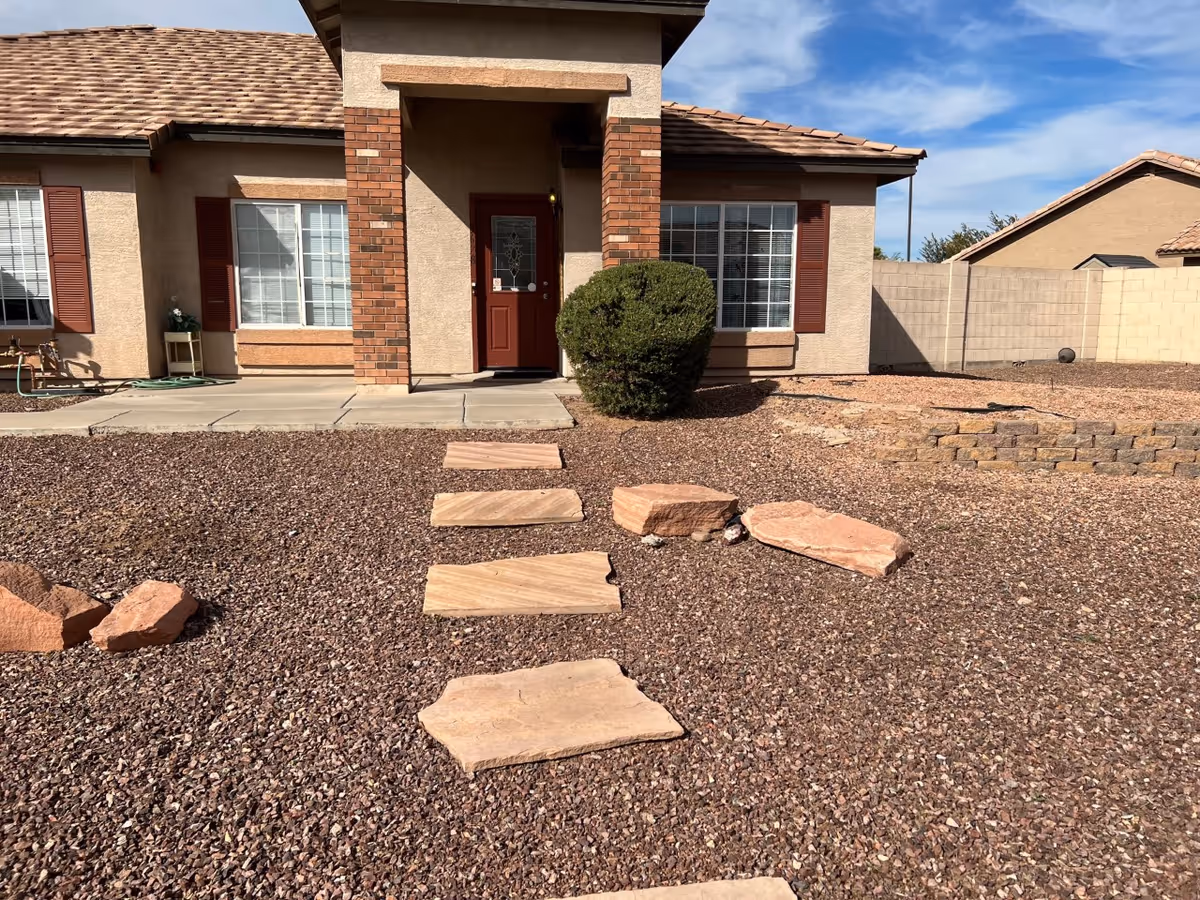 Front entrance of a single-story house with stepping-stone path and xeriscape yard.