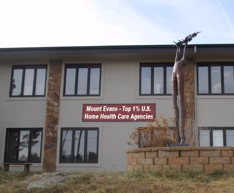 Front exterior of Mount Evans Home Health Care building with a statue and sign.