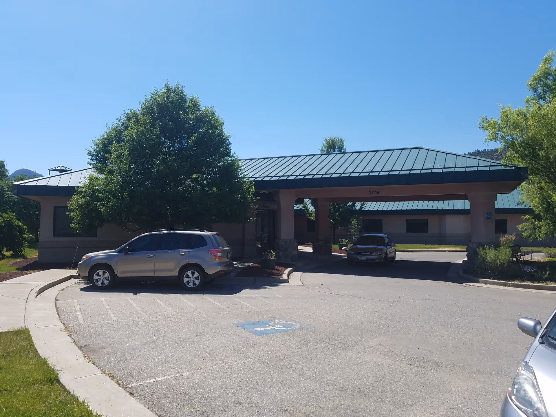 Sunshine Gardens West Assisted Living entrance with a covered drop-off and parked cars.