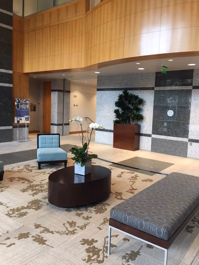 Lobby seating area with blue chair, round coffee table, and plants.