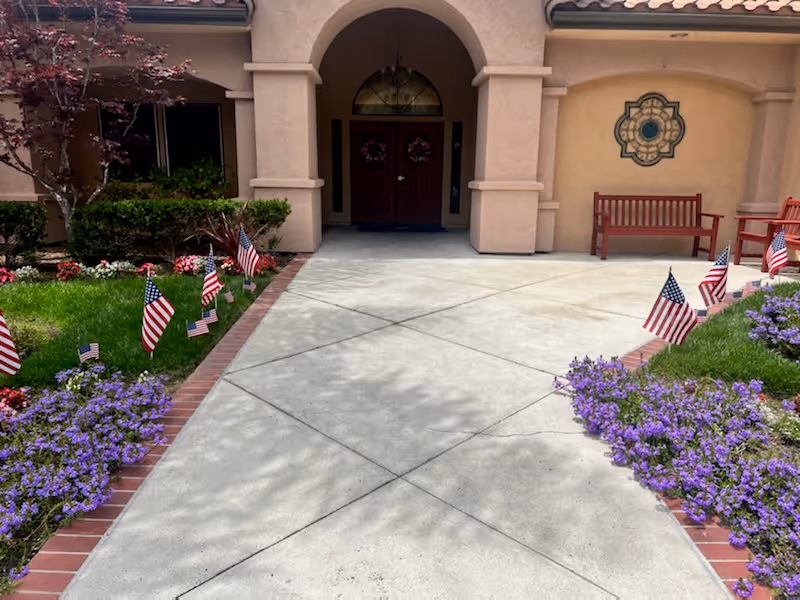Front entrance of Summerfield Memory Care of Encinitas with flags and flowers.