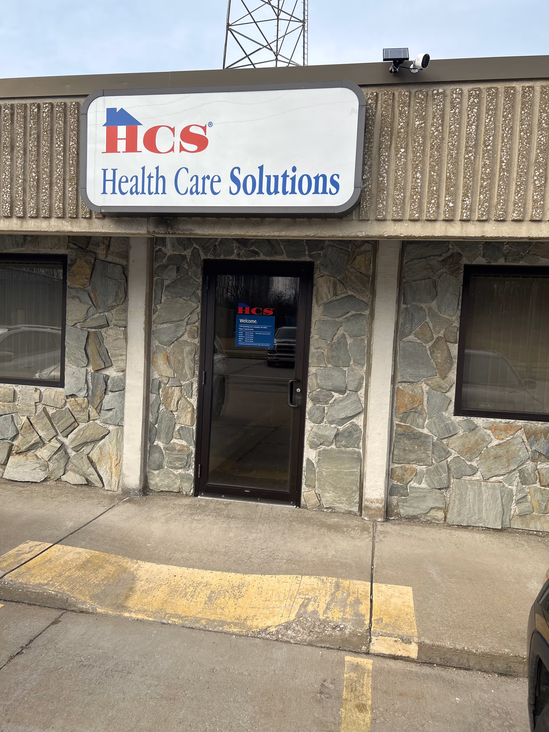 Exterior view of an assisted living facility entrance with HCS Health Care Solutions sign.