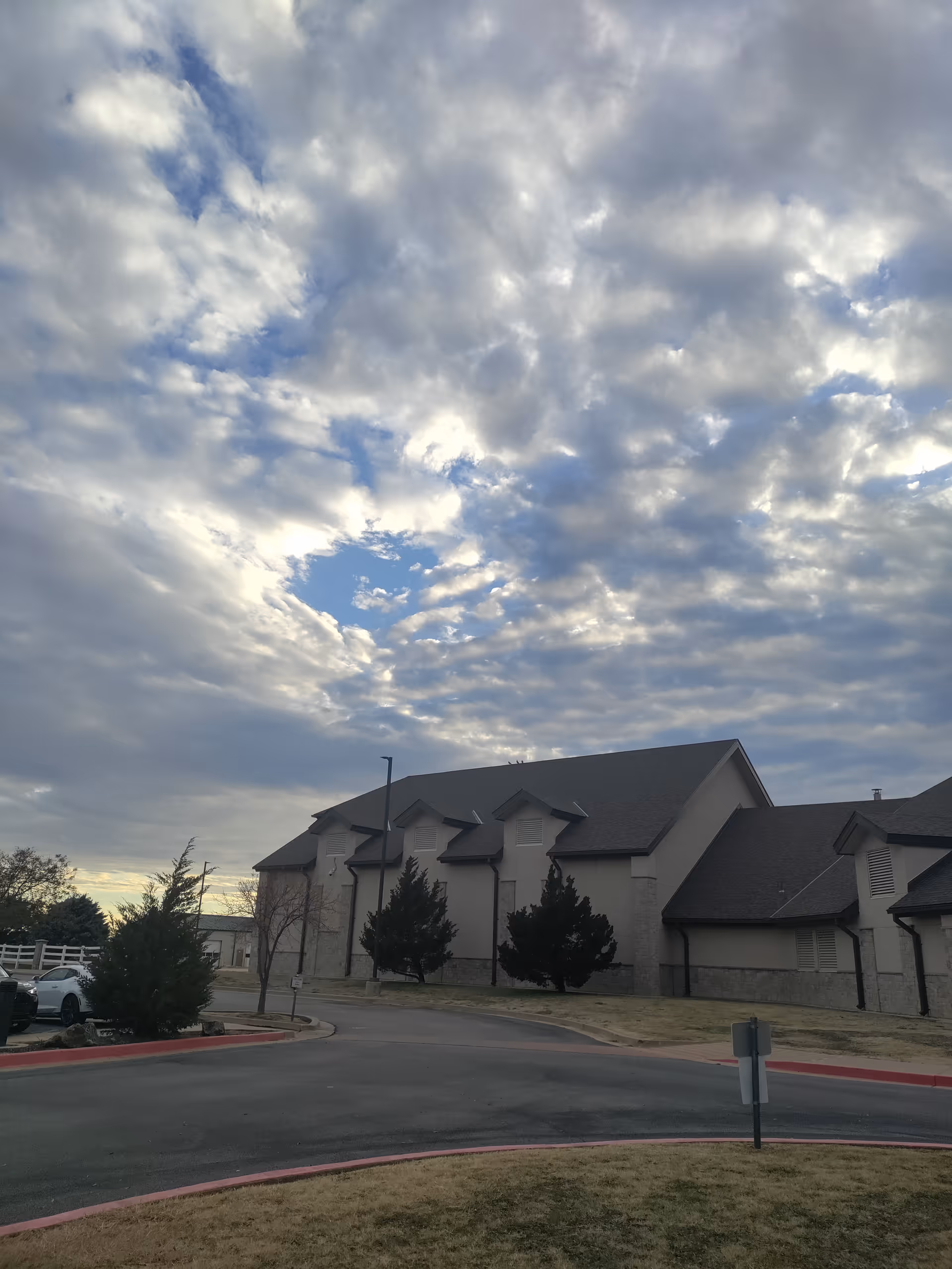 Exterior view of a senior living facility with a gray roof and cloudy sky.