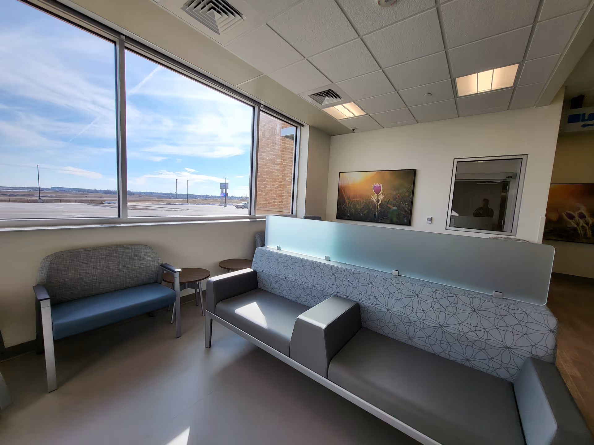Interior waiting area with large windows, modern seating, and a frosted divider.
