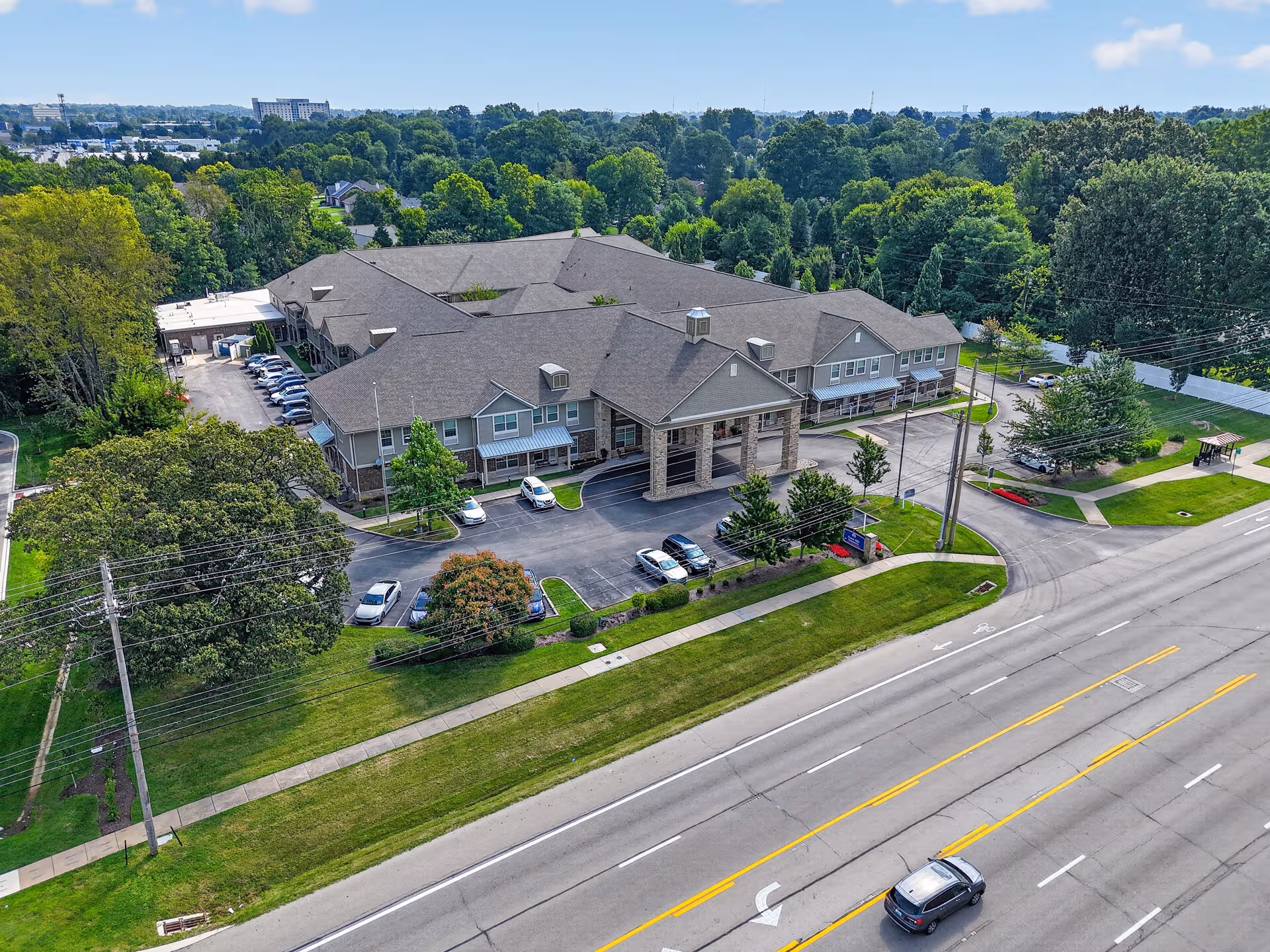 Aerial view of Forest Hills Commons senior living building with parking and trees.